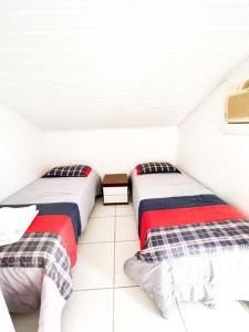 two beds in a room with white walls at Paraíso de luxo: sua casa dos sonhos in Angra dos Reis