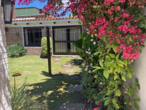 einen Garten mit rosa Blumen an der Seite eines Hauses in der Unterkunft Habitación con baño privado, barbacoa y entrada independiente en carrasco in Montevideo