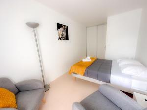 a bedroom with a bed and a couch and a lamp at Mai Linh - TiAM CONCIERGERIE-Disney-VILLIERS SUR MARNE CENTRE VILLE in Villiers-sur-Marne