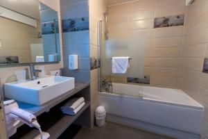 a bathroom with a tub and a sink and a bath tub at Logis Hôtel Le Rochelois in La Rochelle