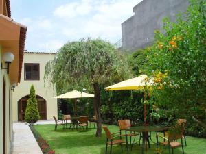 un patio con mesas, sillas y sombrillas en Hotel Meliana, en Arequipa