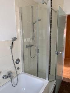 a shower with a glass door next to a white bath tub at FeWo Saier in Althengstett