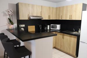 a kitchen with a black counter top and wooden cabinets at Appartement, Lumières d'Arcachon in Arcachon