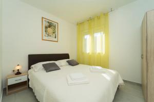 a bedroom with a white bed with two towels on it at SVEMA APARTMAN in Vela Luka