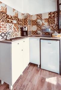 una cocina con armarios blancos y una pared de azulejos en Garsonierele Alexandru, en Saturn