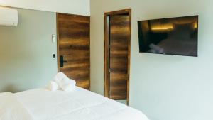 a bedroom with a white bed and a television at I Believe- All Suite Manila-Poblado in Medellín