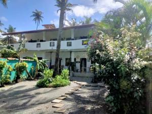 a large white building with palm trees in front of it at The Swiss Lankan in Ahangama