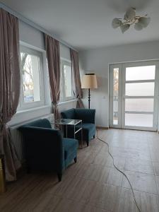 een woonkamer met twee blauwe stoelen en ramen bij VIV Rosetti in Iaşi