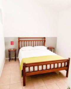 a bed in a bedroom with two tables and a lamp at house with swimmingpool, sauna and games room. in Angra dos Reis