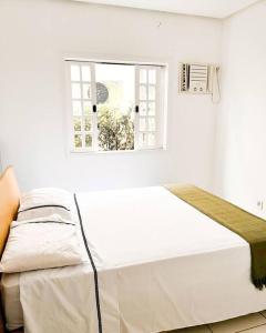 a bed in a white room with a window at house with swimmingpool, sauna and games room. in Angra dos Reis