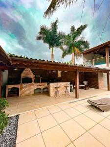 an outdoor patio with a fireplace and palm trees at house with swimmingpool, sauna and games room. in Angra dos Reis