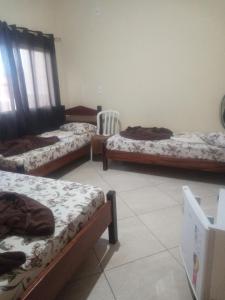 a room with three beds and a chair at Pousada Rota da Luz in Aparecida