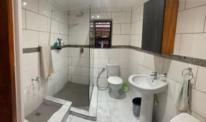 La salle de bains est pourvue de carrelage blanc, de toilettes et d'un lavabo. dans l'établissement 55 On Main, à Sedgefield