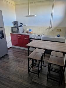 a kitchen with red cabinets and a wooden table and chairs at Bien proche de Aeroport St Exupéry Village de Marques et Lyon in Diémoz