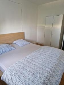 - une chambre avec un lit et une couette blanche dans l'établissement Bien proche de Aeroport St Exupéry Village de Marques et Lyon, 