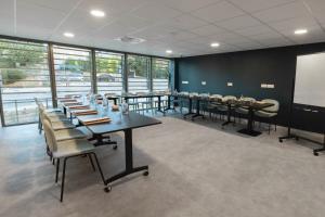 une salle de conférence avec des tables, des chaises et des fenêtres dans l'établissement The Originals Résidence Aix Schuman, à Aix-en-Provence