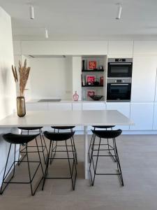 eine weiße Küche mit einer weißen Theke und Hockern in der Unterkunft Beautiful Sunny Penthouse (near Place Albert) in Knokke-Heist