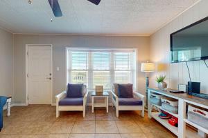a living room with two chairs and a table and a window at IR 110: Seas the Day Port A: 2BR, 2BA, Shared Pool, Boardwalk to Beach, Golf Cart Access in Port Aransas