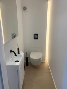 ein weißes Badezimmer mit Toilette und Waschbecken in der Unterkunft Beautiful Sunny Penthouse (near Place Albert) in Knokke-Heist