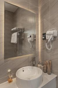 La salle de bains est pourvue d'un lavabo blanc et d'un miroir. dans l'établissement Nét Việt Hotel Vincom Sóc Trăng, à Soc Trang