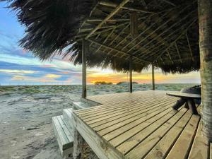 a wooden deck with a straw umbrella on the beach at Arpoador Eco-Lodge in Tutóia