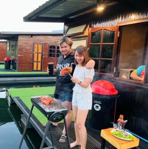 a man and a woman standing next to a grill at Phu Naphat Resort in Tha Kradan