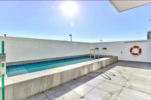 a swimming pool in a white building with a swimming pool at Modern Luxe Getaway for 2 with Stunning Cape Town Views, Fast WiFi, Queen Bed, Voice Control, Chic & Stylish Comfort in Cape Town