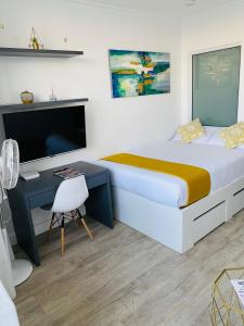 1 dormitorio con 1 cama y escritorio con TV en Modern Luxe Getaway for 2 with Stunning Cape Town Views, Fast WiFi, Queen Bed, Voice Control, Chic & Stylish Comfort, en Ciudad del Cabo