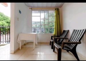 Zimmer mit 2 Stühlen, einem Tisch und einem Fenster in der Unterkunft Hostal Cartagena Beach in Cartagena de Indias