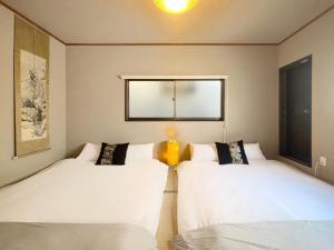 two beds in a room with a window at guesthouse Chikko - Vacation STAY 15111 in Osaka