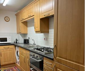 a kitchen with wooden cabinets and a stove top oven at Dundee City Waterfront, 2 Bedroom 2 Bathroom Apartment - Parking and WIFI, short walk to V and A, Bus & Train Stations in Dundee