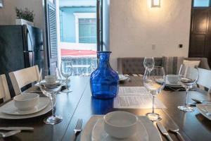 Family Getaway Apt - La Fortaleza Old San Juan - Fort Apt 4 في سان خوان: وجود مزهرية زرقاء على طاولة مع كؤوس للنبيذ