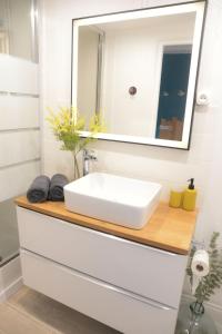 een badkamer met een witte wastafel en een spiegel bij L'authentique ! - Ma petite résa in Vesoul