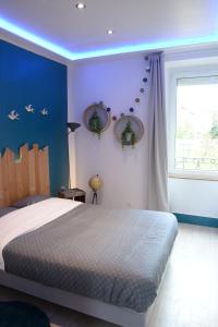 een slaapkamer met een bed met blauwe muren en een raam bij L'authentique ! - Ma petite résa in Vesoul