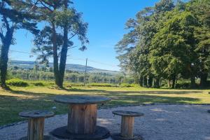 a picnic table and two stools in a park at Petit Lough Arrow cottage 