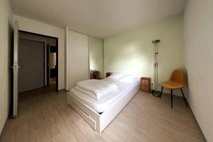 a bedroom with a white bed and a chair at Appartement 2 chambres centre in Pessac