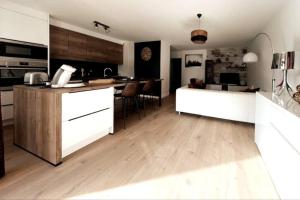 a kitchen with white cabinets and a wooden floor at Appartement 2 chambres centre in Pessac