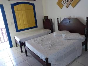 um quarto com duas camas e uma porta amarela em Pousada Recanto da Cleide em Paraty