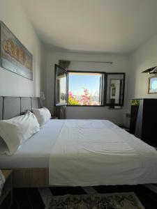 a bedroom with a large white bed with a window at Appartement maria marina in Sousse