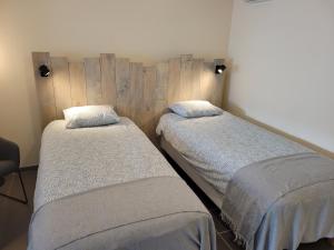 two twin beds in a room with wooden walls at Gite de la chapelle blanche 