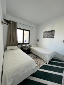 a bedroom with two beds and a window at Appartement maria marina in Sousse +7 photos
