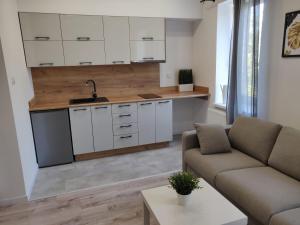 una cucina con armadi bianchi e un soggiorno con divano. di Konopnickiej 9 Studio z antresolą PTAK, Orientarium, Atlas ARENA, Szpital, Mandoria, Fala, Centrum Zdrowia Matki Polki, Rodzina, Family, bezpłatny parking a Pabianice