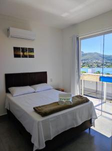 a bedroom with a large bed with a large window at Pousada Vale do Sol Capitólio in Capitólio