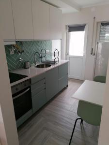 a kitchen with white cabinets and a sink and a table at Baleal Atlantic 6 in Baleal
