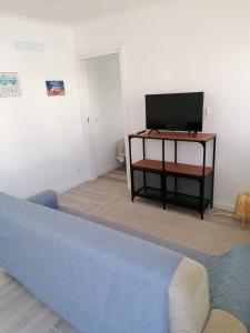 uma sala de estar com um sofá azul e uma televisão em Baleal Atlantic 6 no Baleal
