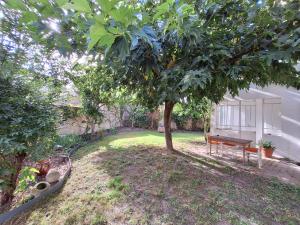 a yard with a bench next to a tree at La Maison Partagée d'Arlac in Mérignac