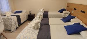 una habitación con 3 camas con animales de peluche. en Pensión Mar, en Portomarín