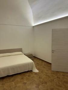 a white bedroom with a bed and a door at La Casetta in Ordona