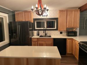 eine Küche mit Holzschränken und einem schwarzen Kühlschrank in der Unterkunft Riverside Retreat in Benton Harbor