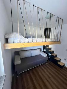 a loft bed with a couch under a shelf at Apartman Winter Nights Vlašić in Vlasic